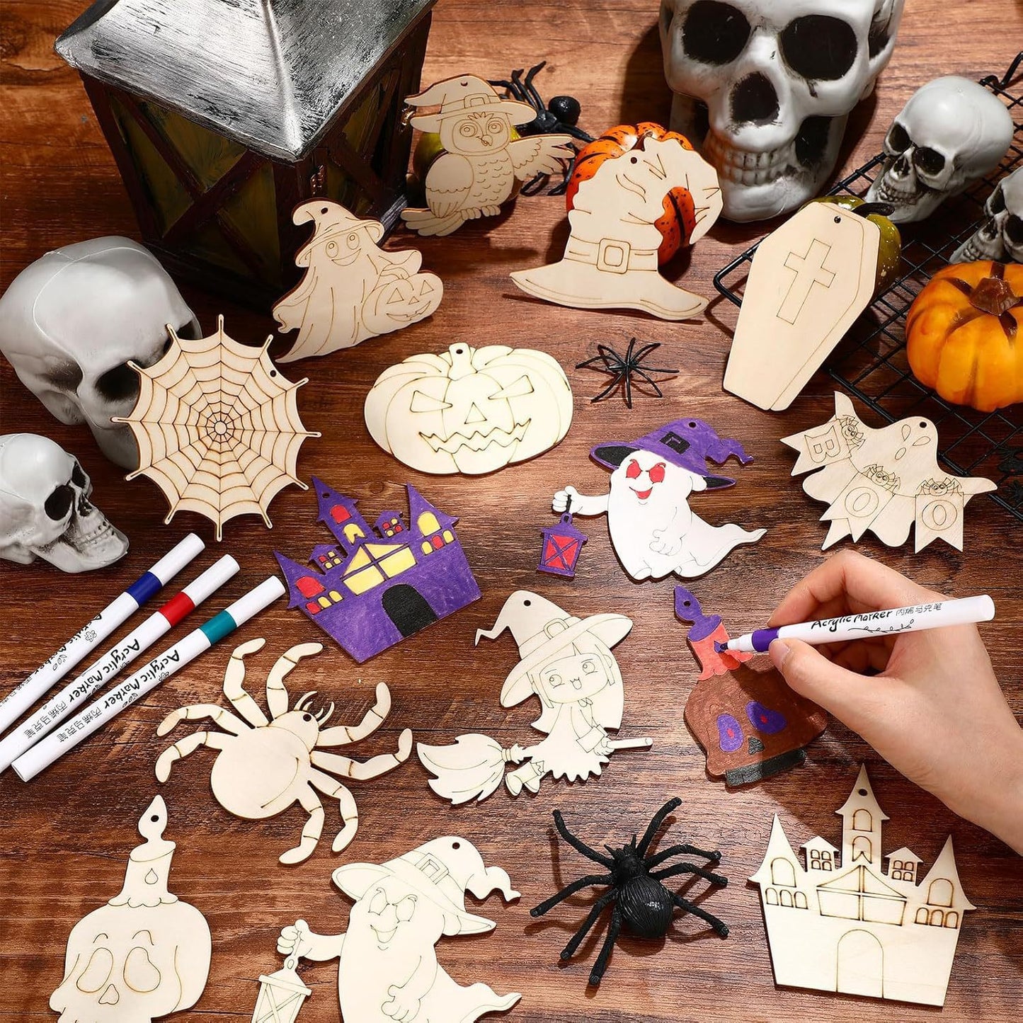 Halloween wooden craft ornaments laid out on table: ghost, skull, spider web, pumpkin