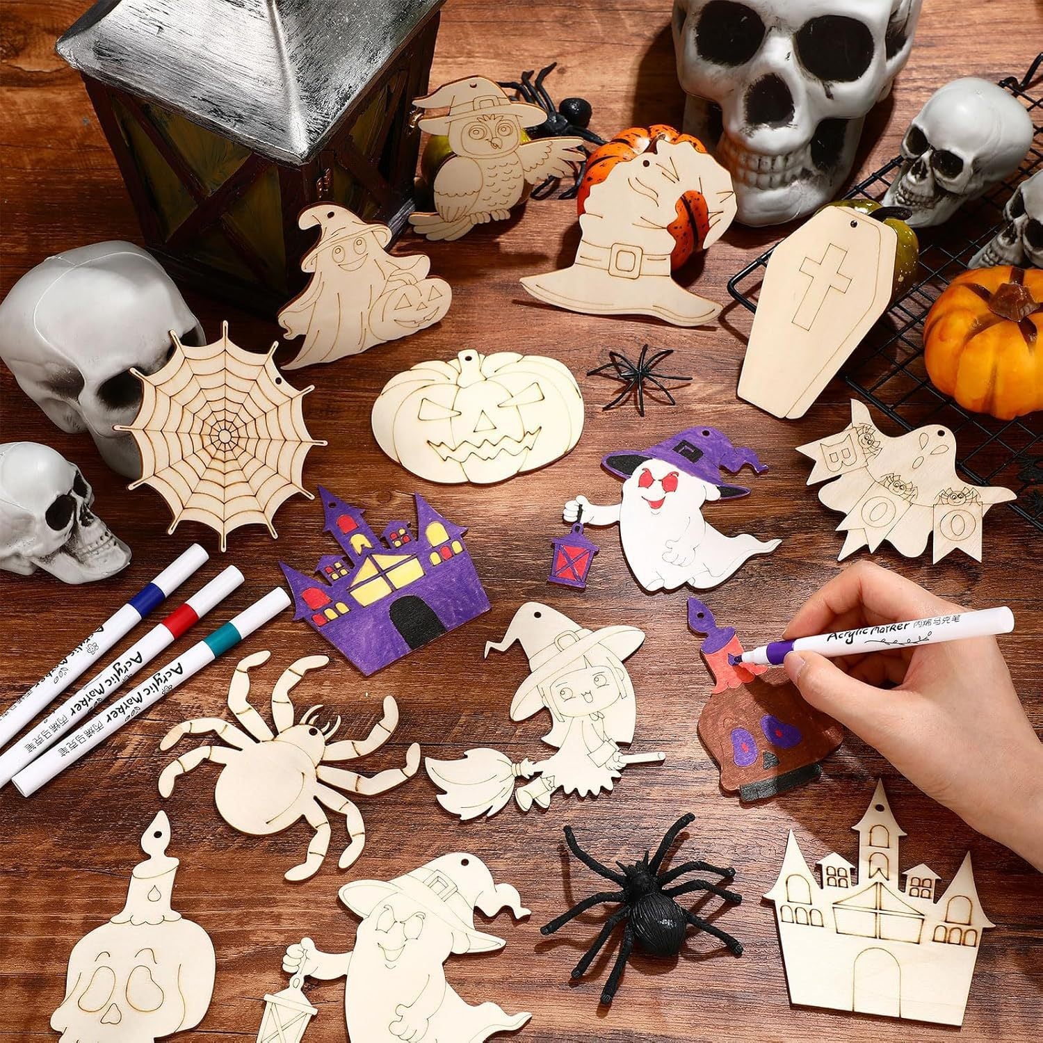 Halloween wooden craft ornaments laid out on table: ghost, skull, spider web, pumpkin