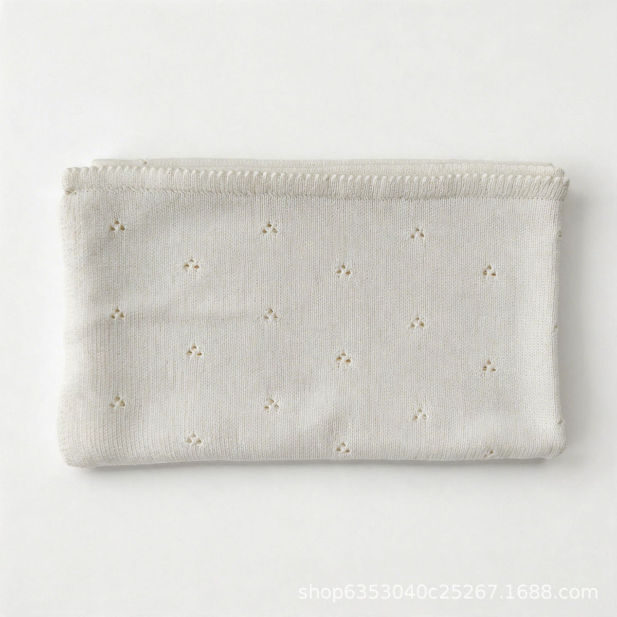 White cotton baby blanket with small hollow floral embroidery, neatly folded