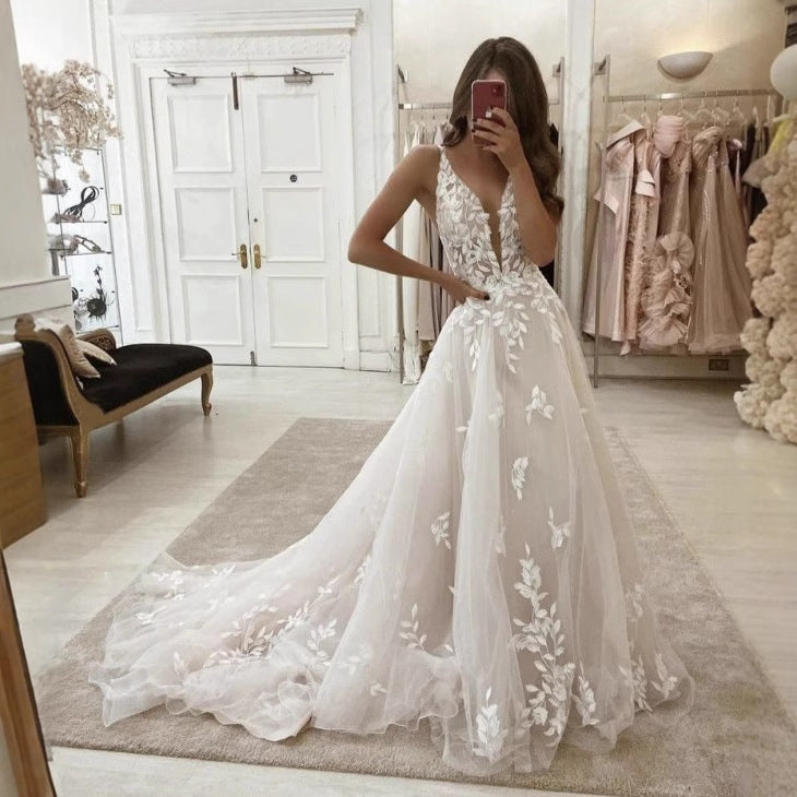 White wedding dress with plunging V-neck, floral lace appliqué, and long train