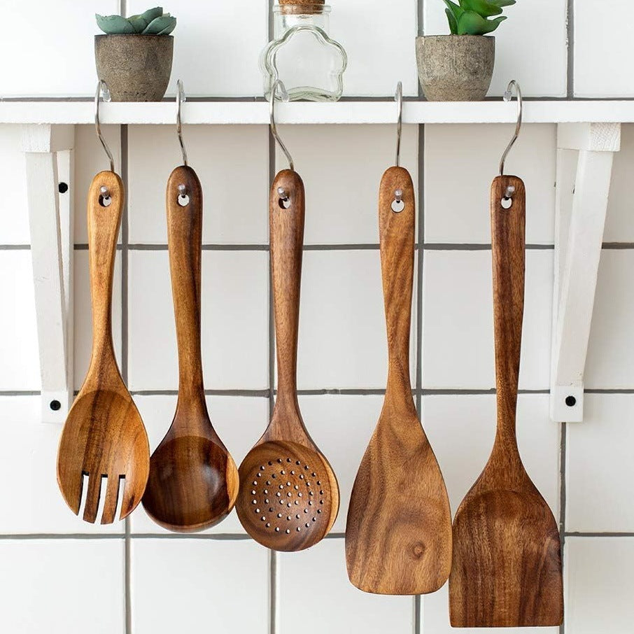 Wooden kitchen utensils hanging on hooks: ladles, spoons, and spatulas