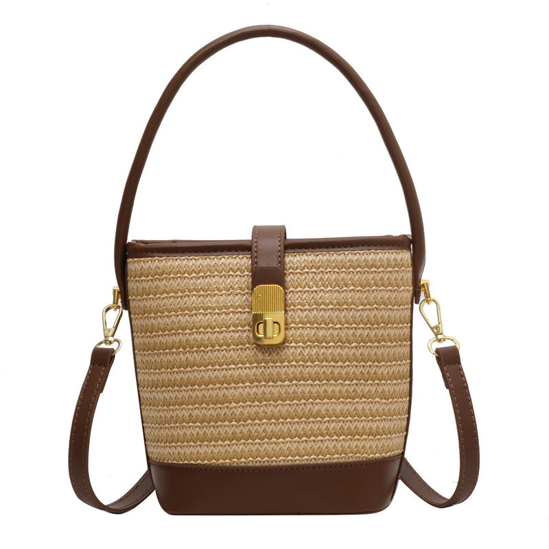 Khaki woven bucket bag with brown leather base, top handle, and crossbody straps.