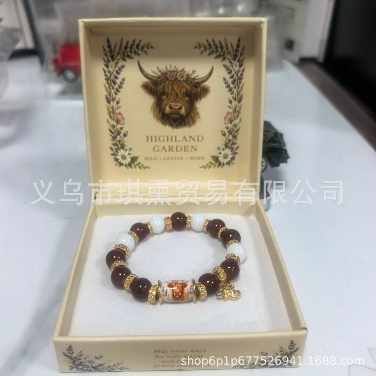 Beaded lucky bracelet with dark brown and cream beads and a small gold horned-animal charm