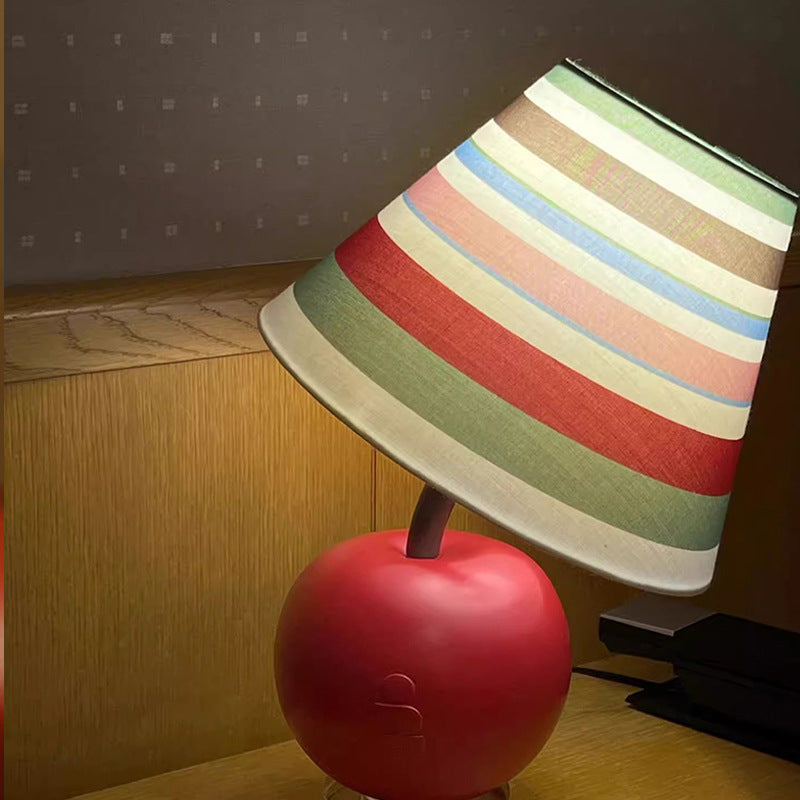 Apple-shaped bedside lamp with multi-color striped fabric shade and red base.