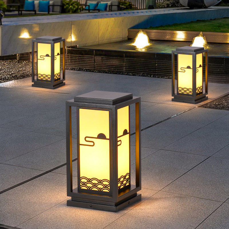 Solar lantern light in black frame with warm glow, decorative bottom pattern on patio