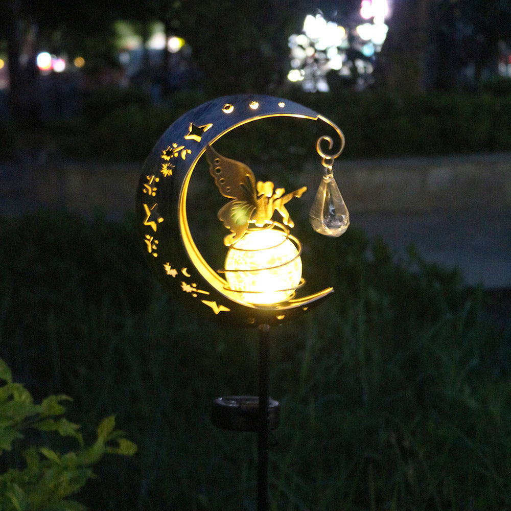 Solar moon garden lamp glowing at night with gold fairy motif and glass globe