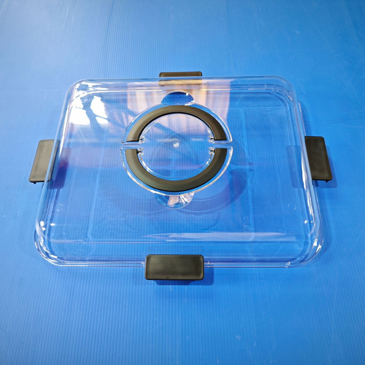 Bamboo charcuterie board with clear lid and black side clips, top view