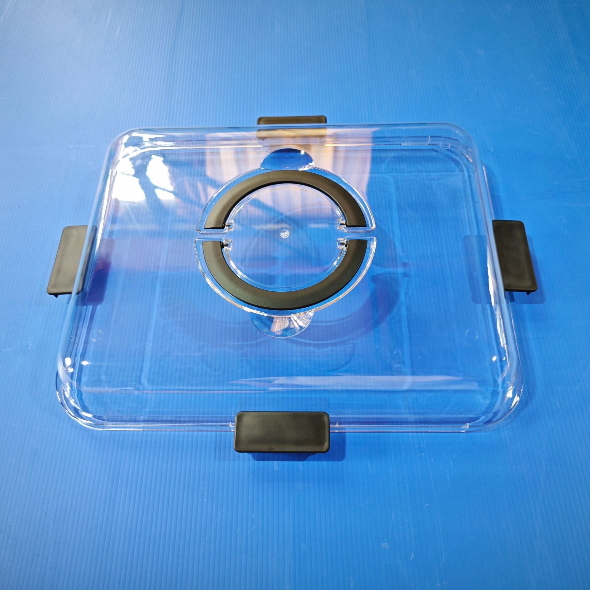 Bamboo charcuterie board with clear lid and black side clips, top view