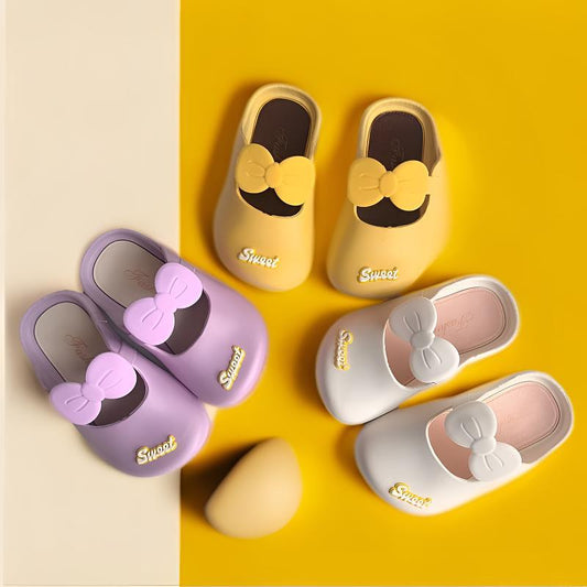 Girls' indoor bow slippers—yellow, purple, and white pairs with soft non-slip soles