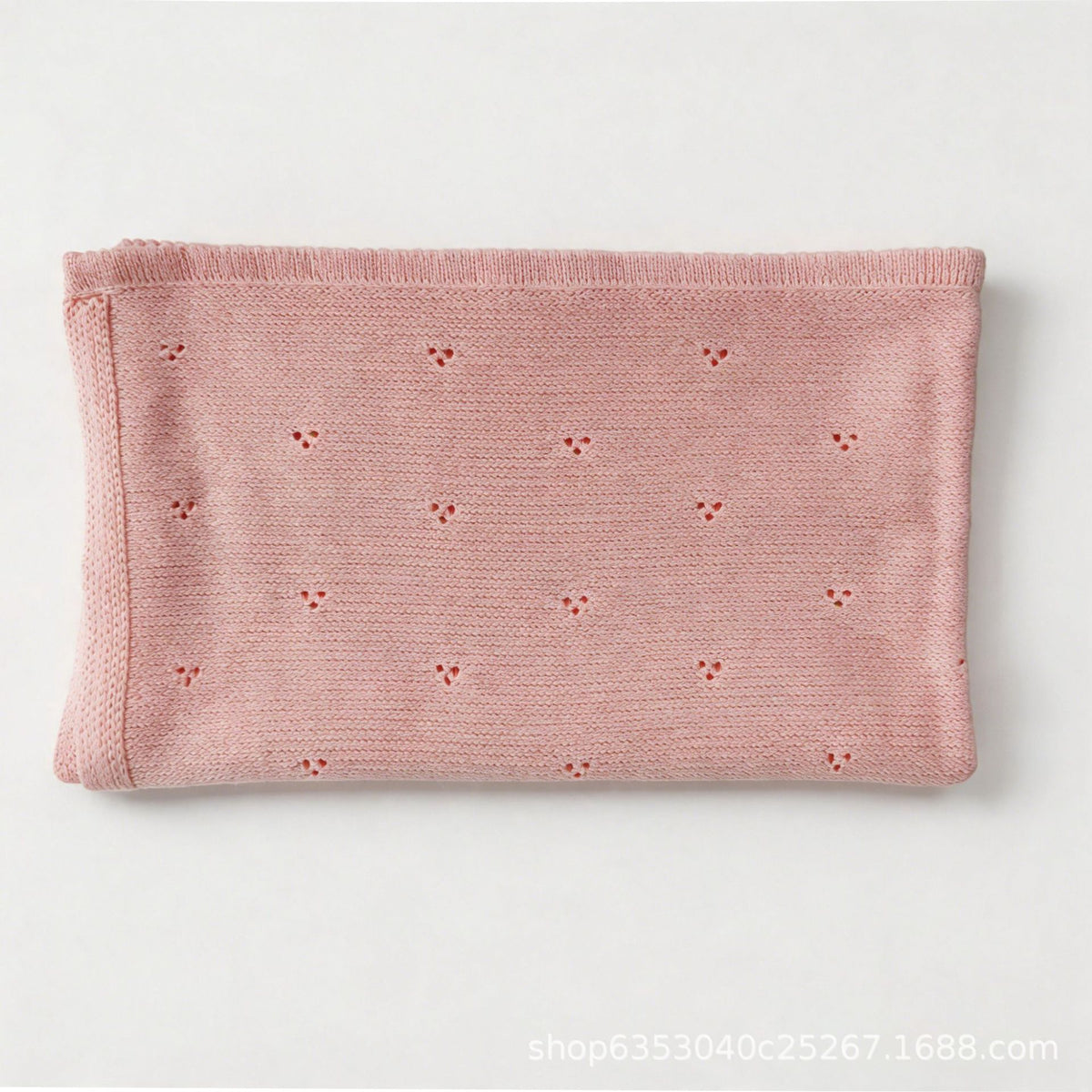 Pink cotton baby blanket with small hollow floral embroidery, neatly folded