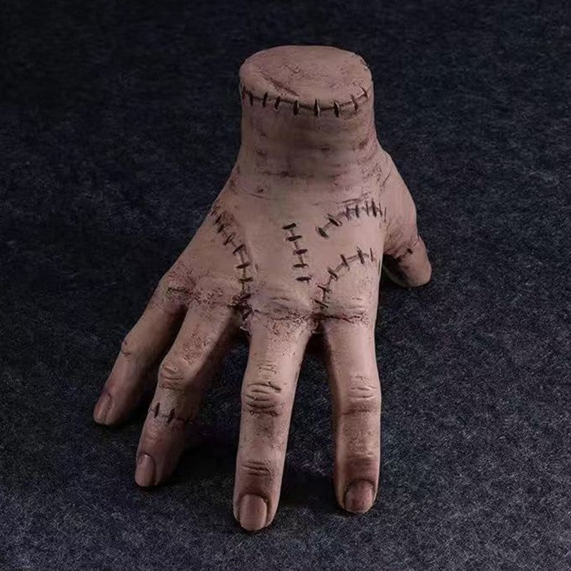 Halloween severed hand prop, dark flesh color with stitched seams across wrist and palm.