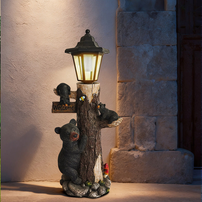 Solar garden light ornament by stone wall: lantern over hugging koalas on a wooden log