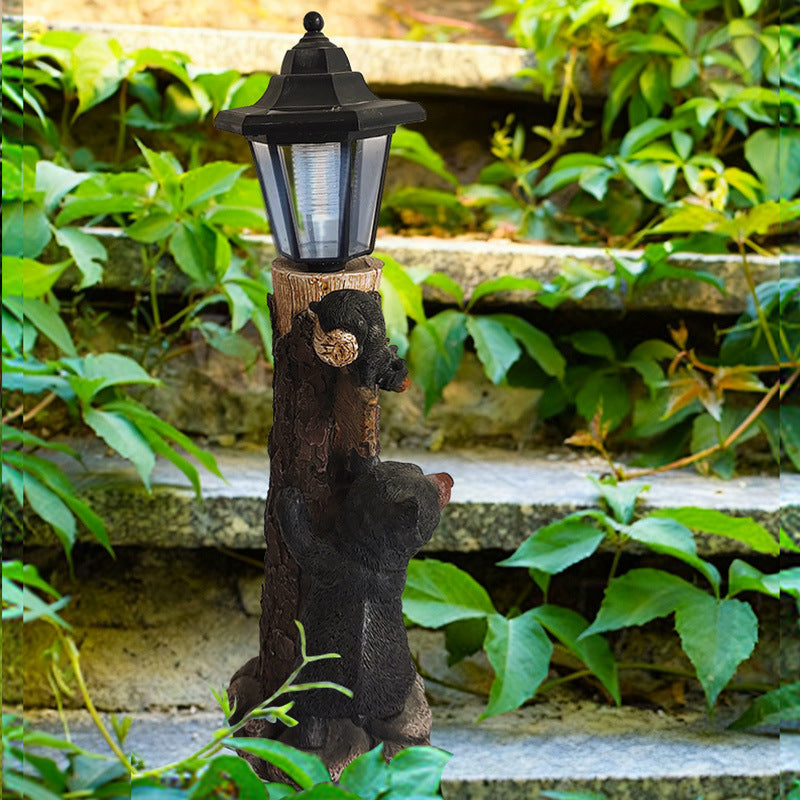 Solar garden light ornament detail: lantern atop wooden log with black koala figure