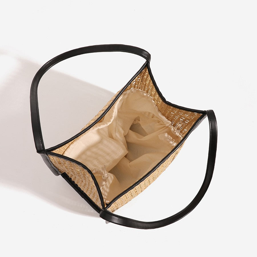 Open woven tote bag interior with tan lining and black trim, curved shoulder handles