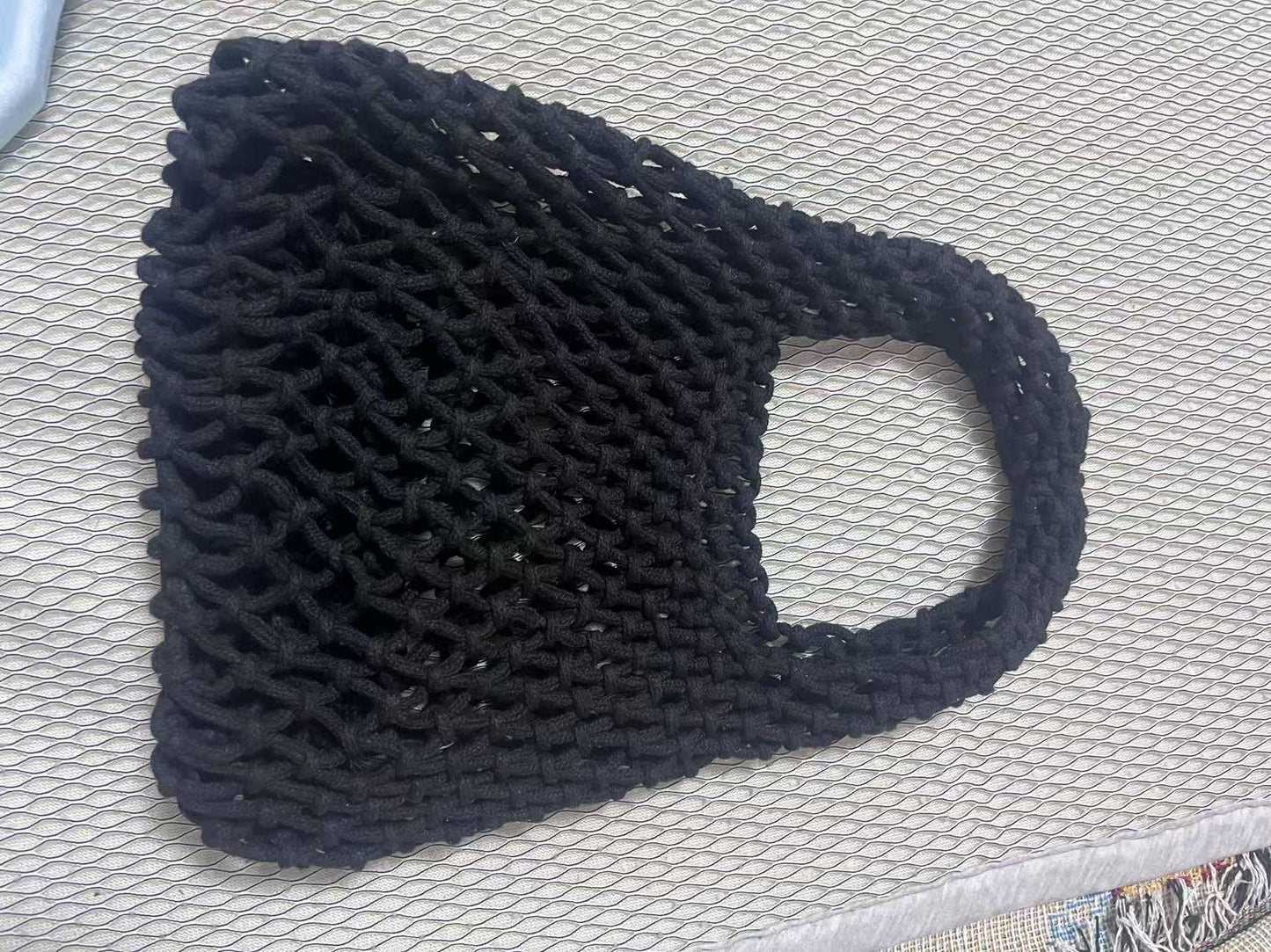 Navy woven cotton rope bucket bag with hollow net texture and loop handle.