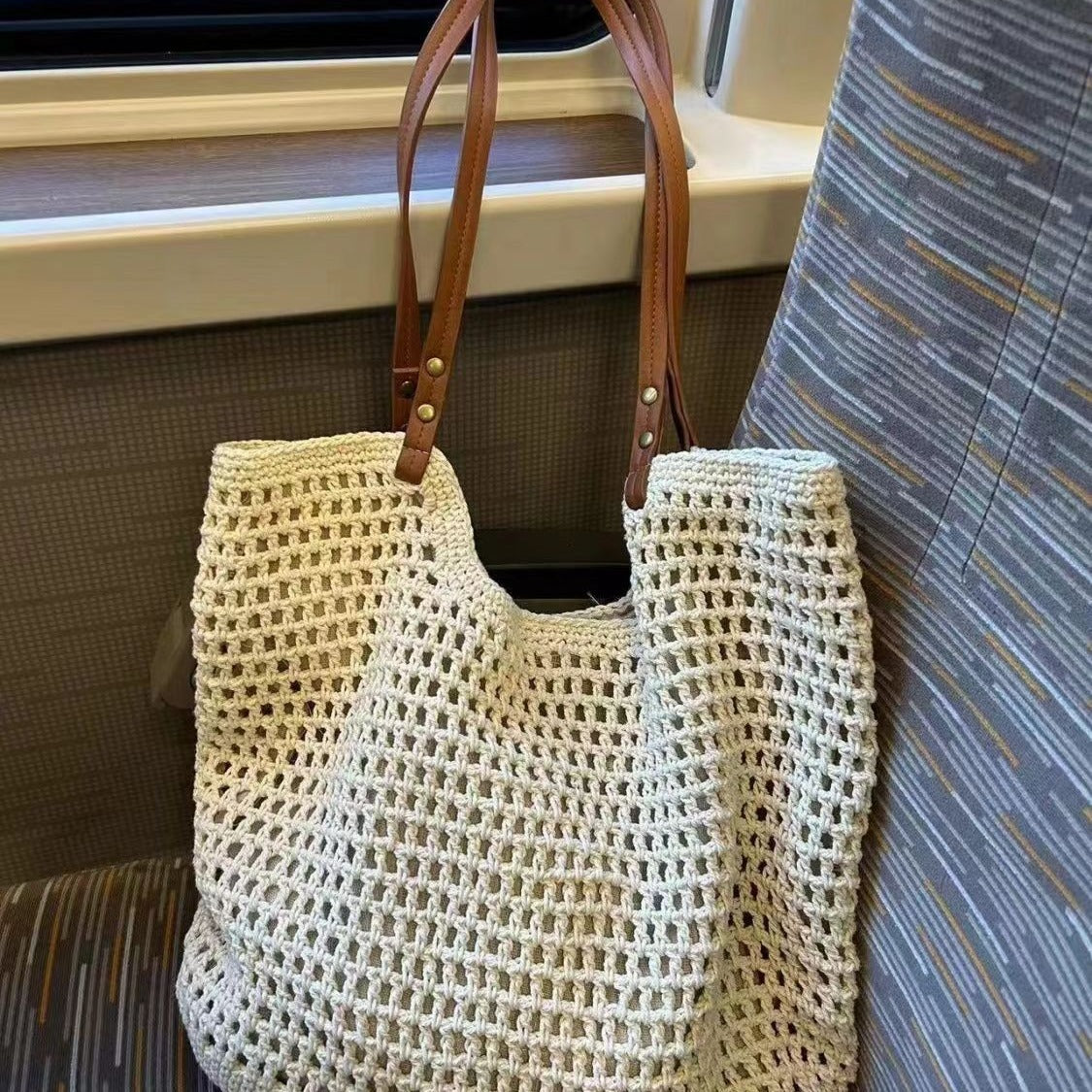 Off-white woven mesh tote bag with sturdy bottom and brown leather handle straps