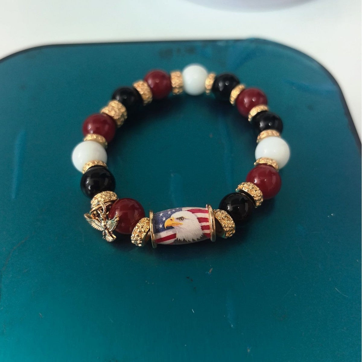 Beaded elastic bracelet with maroon, white, and black beads and a bird charm center
