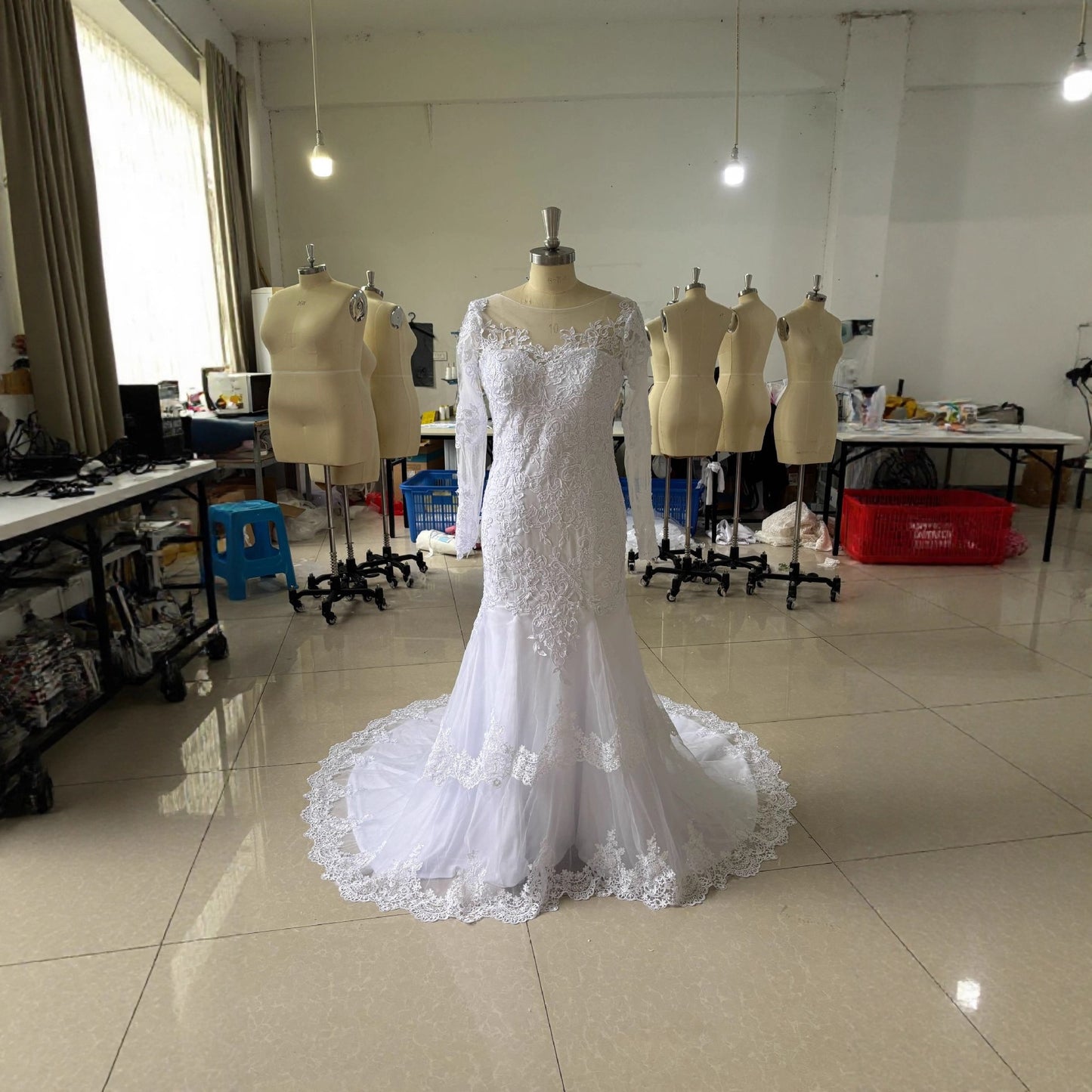 White mermaid wedding dress on mannequin with lace bodice and flowing lace train