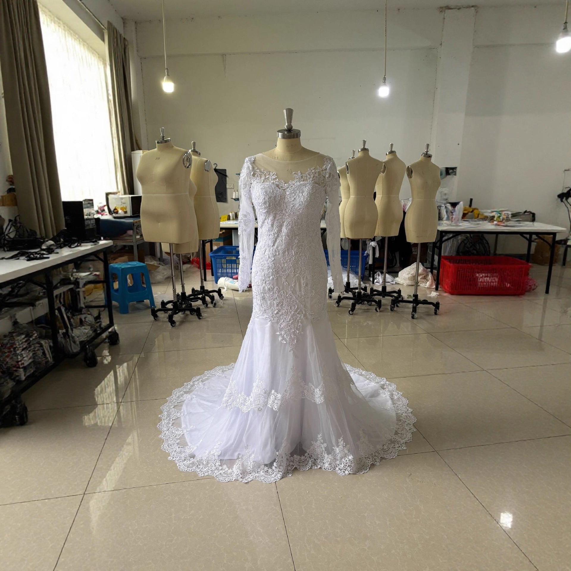 White mermaid wedding dress on mannequin with lace bodice and flowing lace train