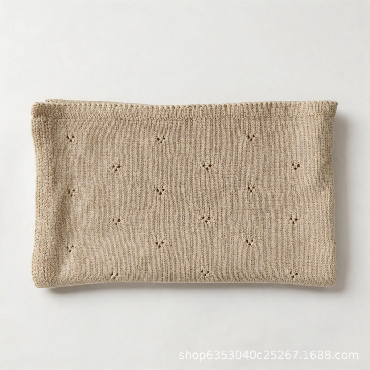 Light oatmeal cotton baby blanket with small hollow floral embroidery, neatly folded