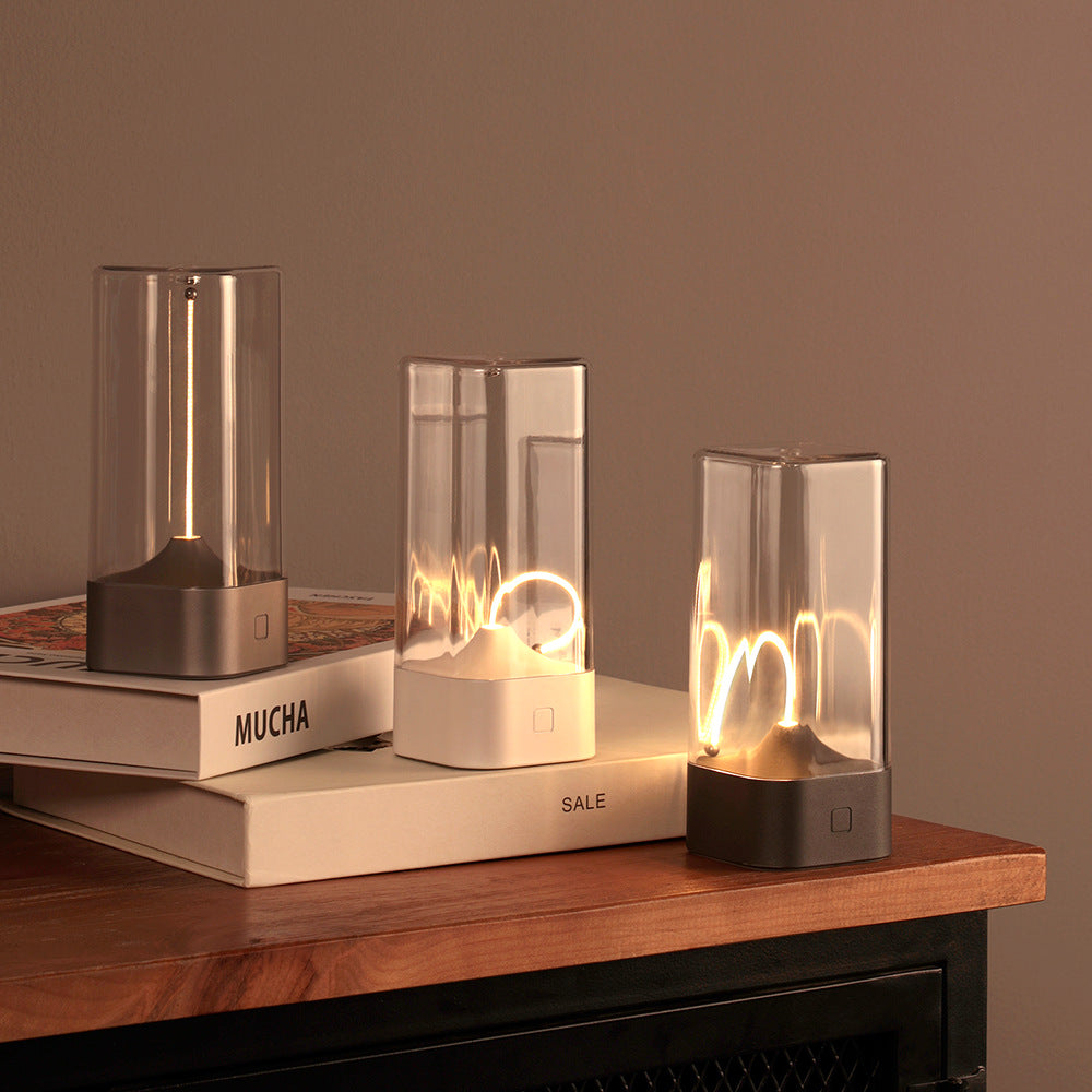 Portable LED night light with clear glass cylinder and dark base, warm glow in an enclosed frame