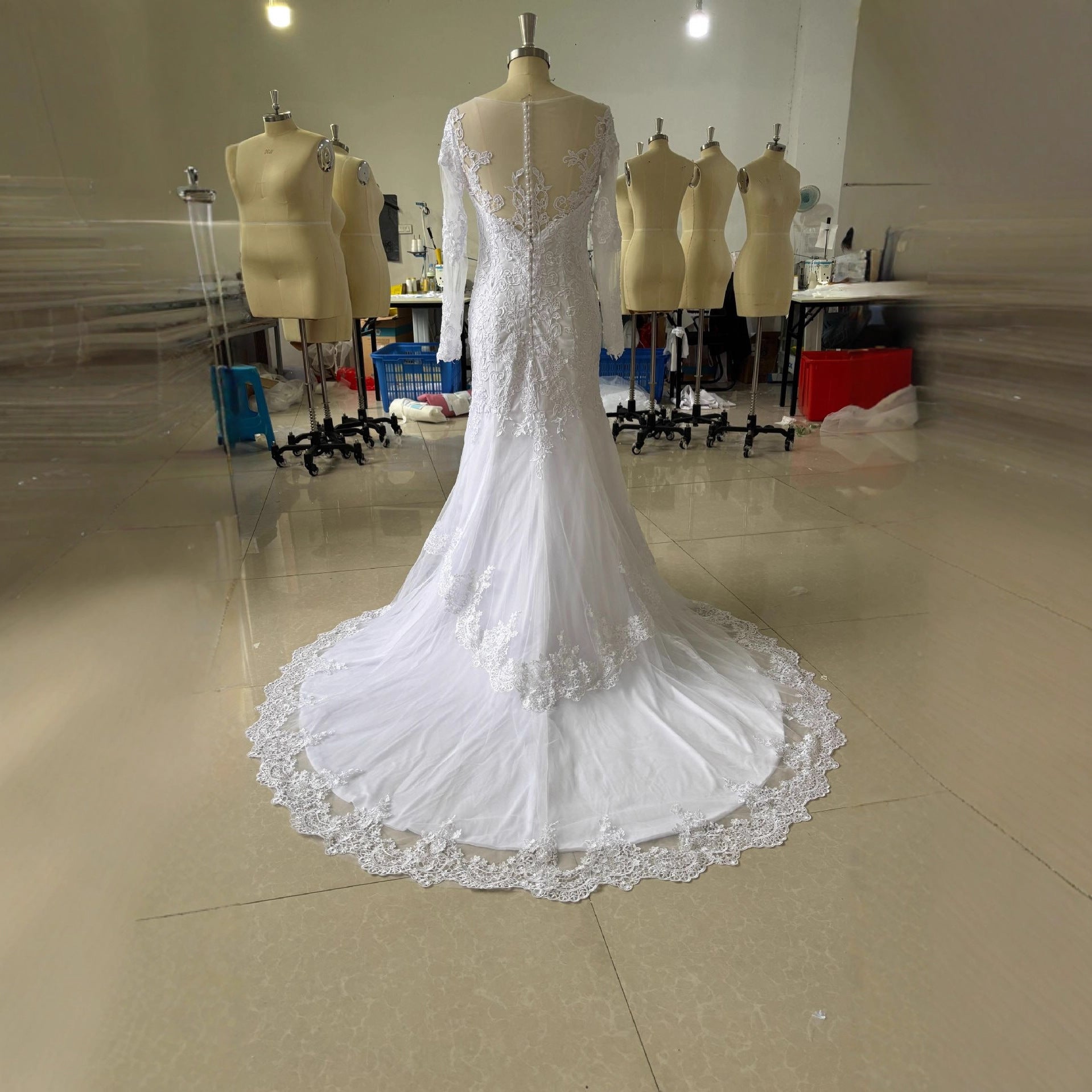 White mermaid wedding dress on mannequin with long lace sleeves and flared lace hem