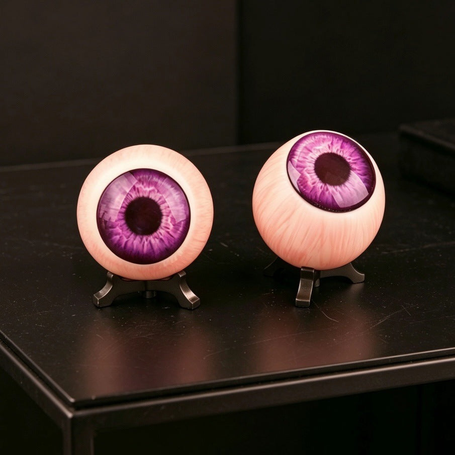 Pair of resin purple eyeball ornaments with violet irises on black stands