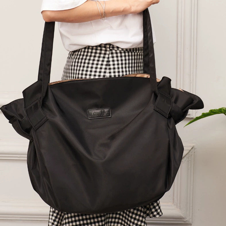 Black large-capacity travel duffel bag with reinforced handles and front pocket detail