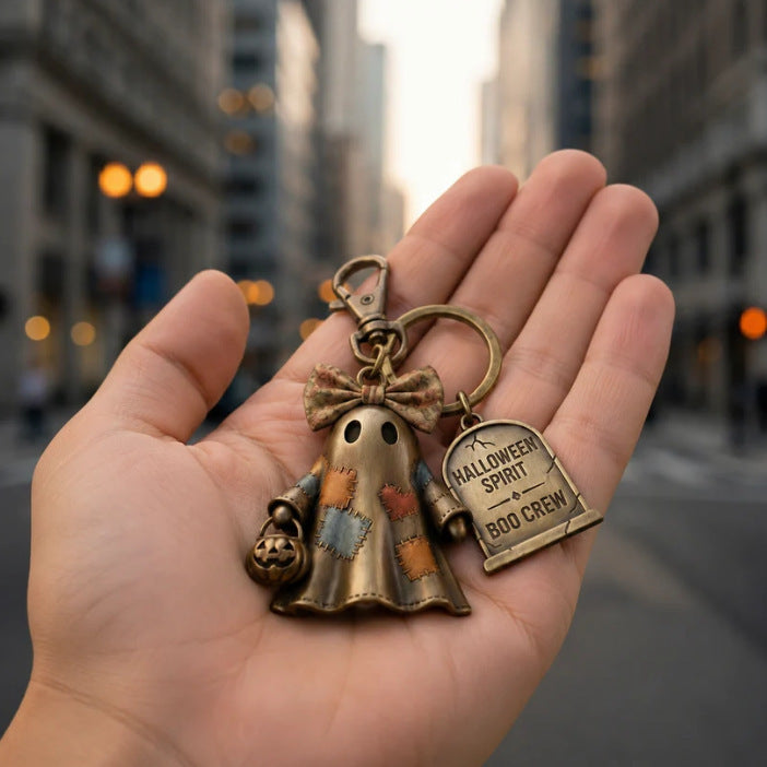 Halloween ghost keychain charm shown in open palm, bronze ring with Boo Crew tag