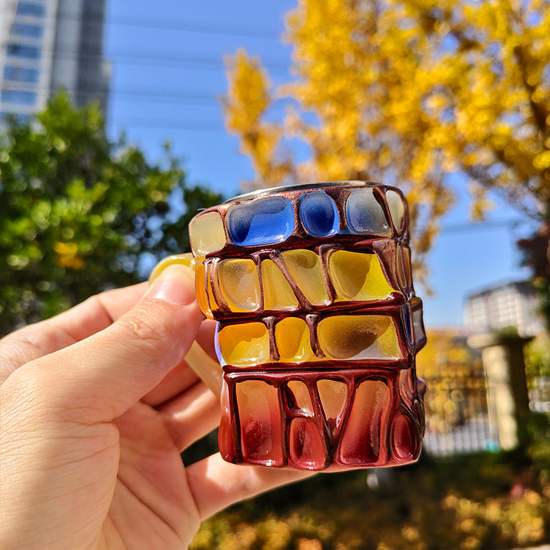 Amber and blue book-stack resin mug with red lower layer, held upright.