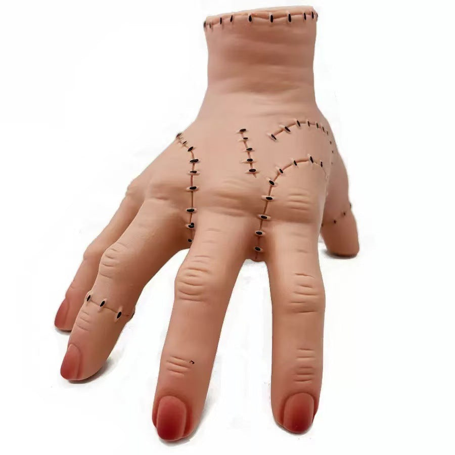 Halloween severed hand prop, pale flesh tone with stitched lines on fingers and wrist.
