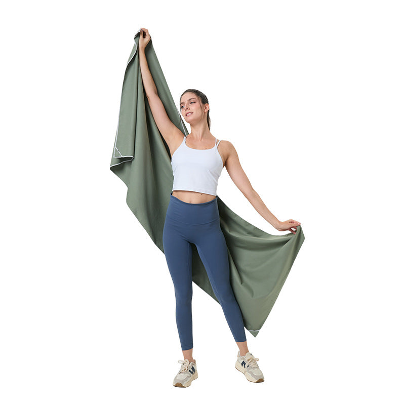 Quick-dry microfibre beach towel, olive green, held overhead by a person