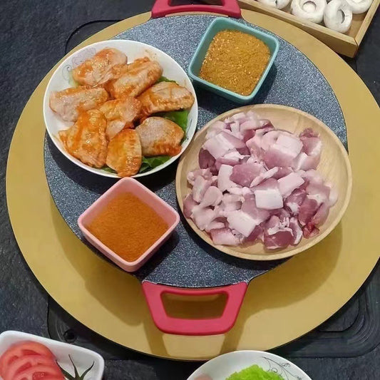 Round electric non-stick baking tray with red handles, cooking surface with grilled foods