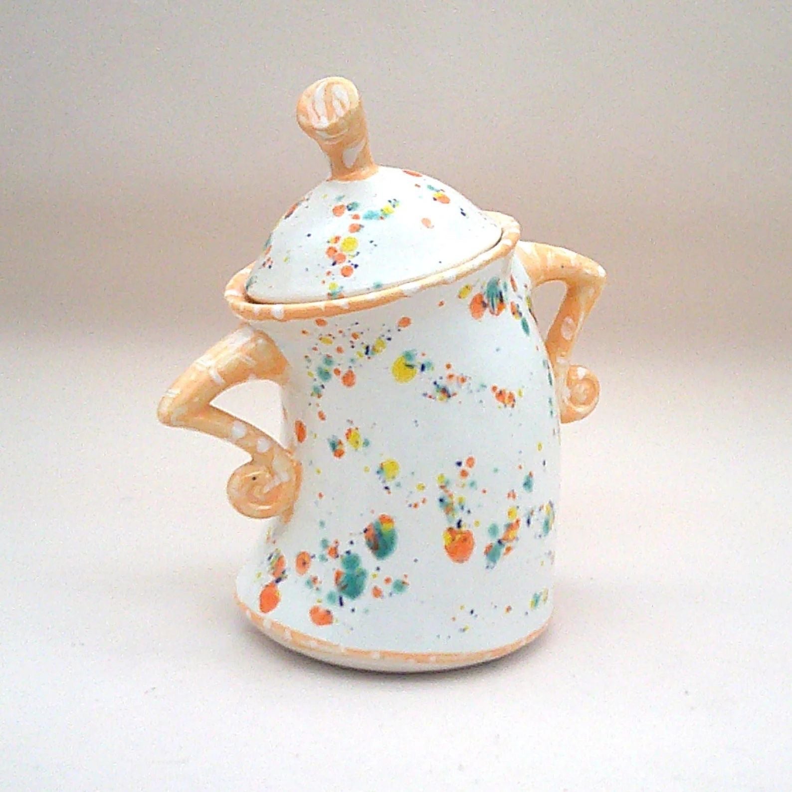Decorative resin lidded jar, white with multicolor splatter, tan handles and finial lid