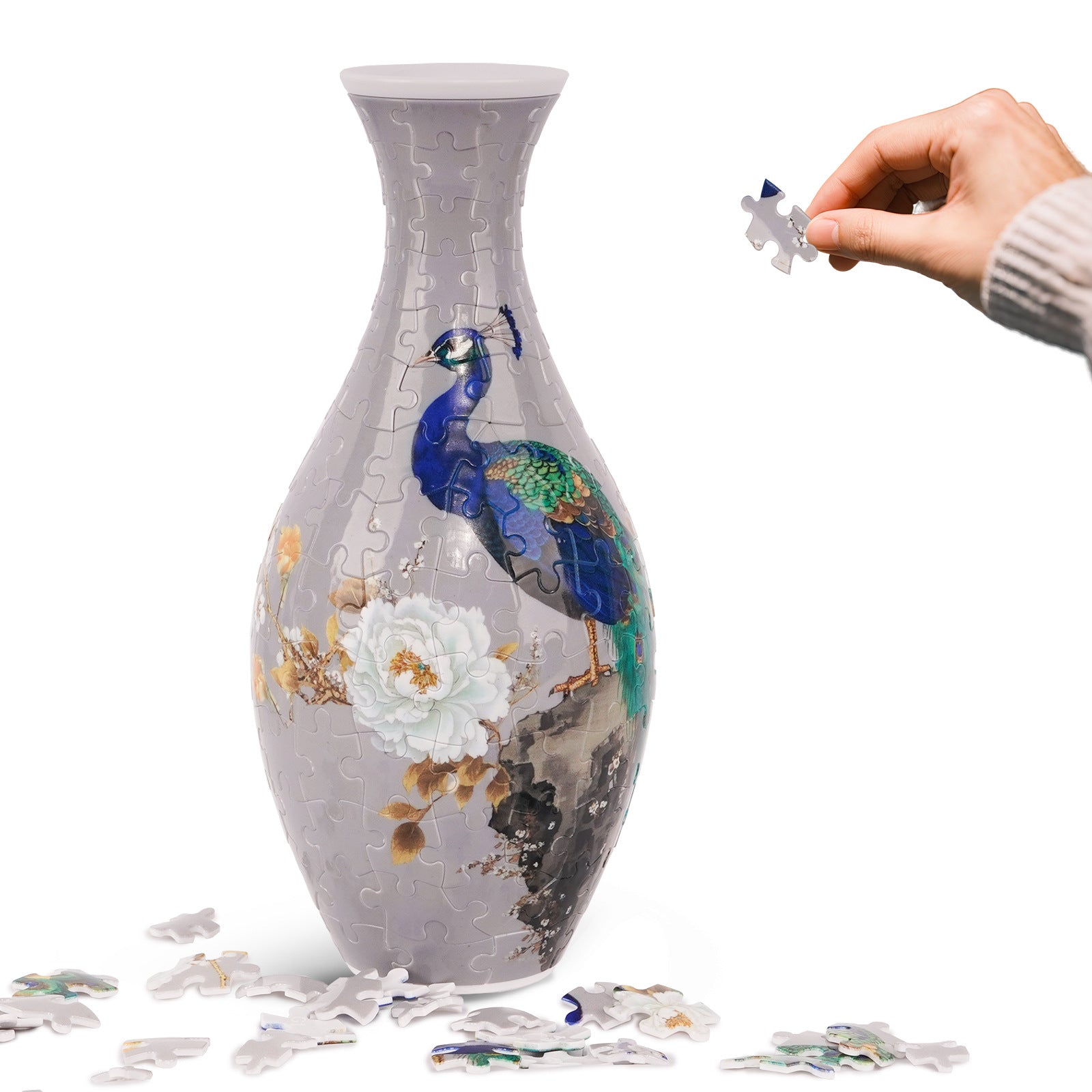3D puzzle vase, white with blue bird and floral scene; hand placing a puzzle piece