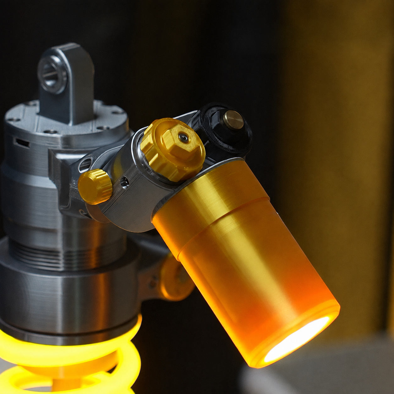 Shock absorber desk lamp with glowing amber bulb and gold-and-gray metal housing