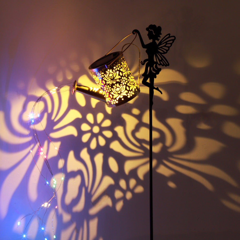 Warm glowing solar projection lamp casting floral patterns from bronze lantern and black fairy stake