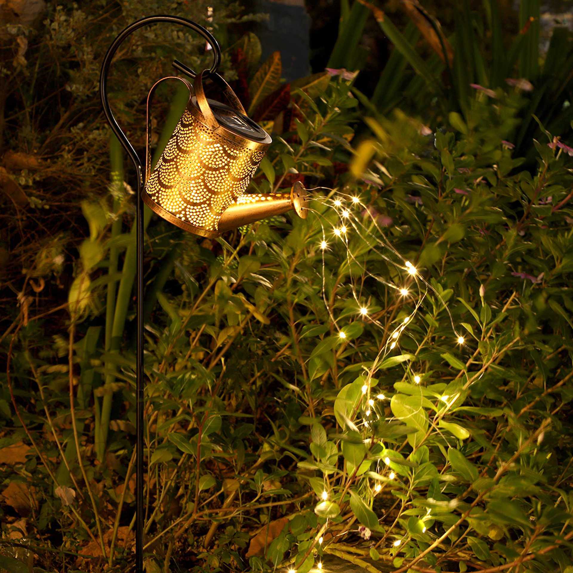 Copper perforated solar lantern projection lamp casting warm lights over green foliage