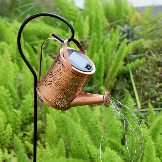 Copper perforated solar lantern projection light on black stake, glowing in garden greenery