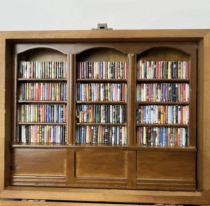 Brown wooden display bookcase with open shelves and books; lower cabinets below