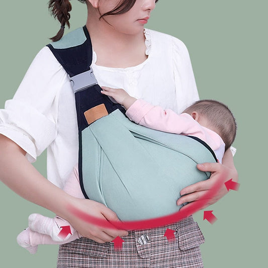 Adjustable baby shoulder carrier sling with green pouch and navy straps, baby seated.