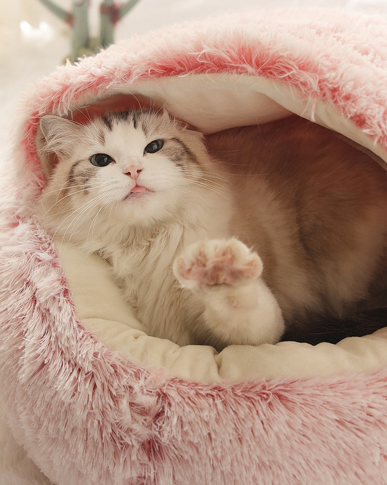 Pink plush pet bed with tunnel entrance, cat resting inside close-up