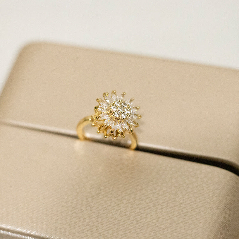 Gold sunflower fidget ring closeup with crystal center on beige fabric