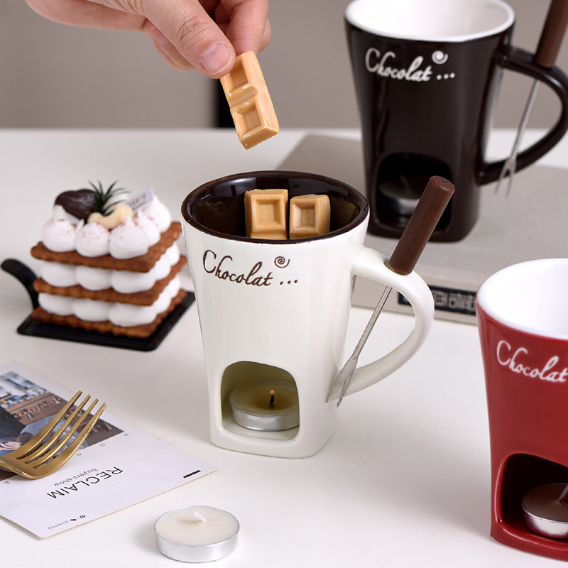 White mini fondue mug holding chocolate pieces over lit warmer