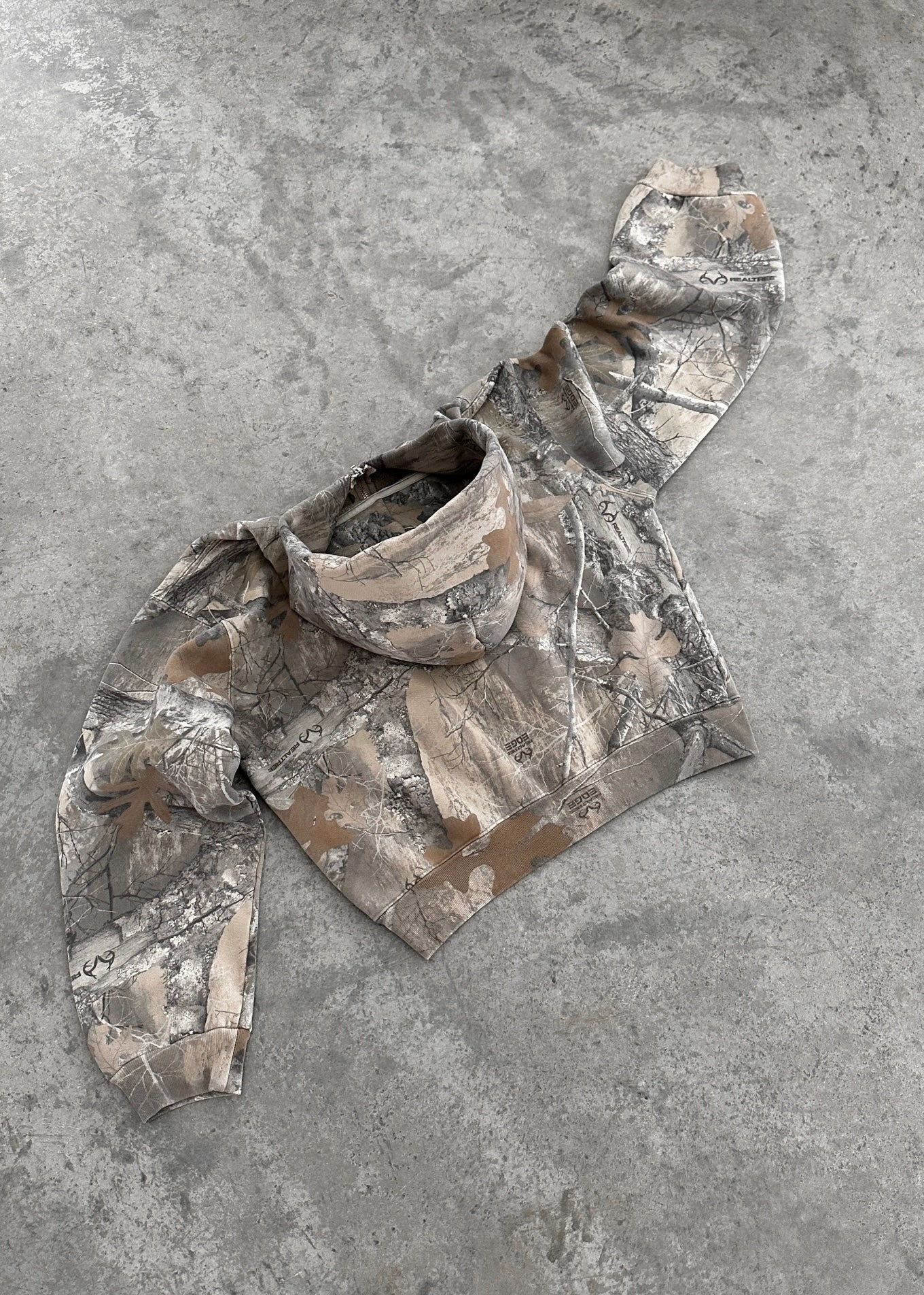 Camouflage hoodie laid flat, attached hood and long sleeves, gray tan tree print