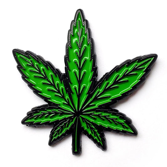 Green cannabis leaf soft enamel fridge magnet on dark metal backing