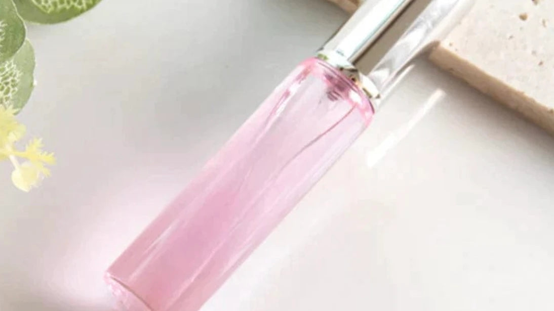 Pink perfume roller bottle with silver cap, angled view