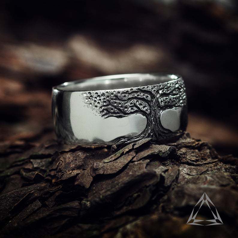 Wide carved ring with Tree of Life motif, dark antique silver finish, close-up.