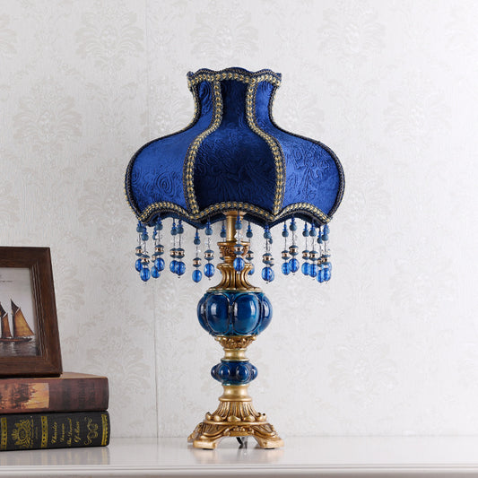 Blue resin table lamp with ornate fabric shade, gold trim, and hanging crystal drops