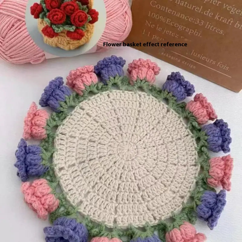 Crocheted coaster with cream center, green rim, and blue and pink rose-like crochet clusters